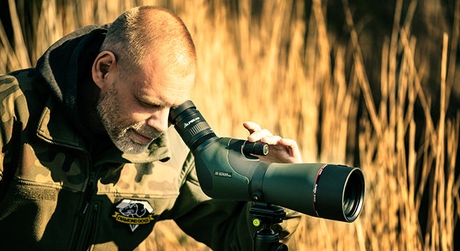 Bearded man looking through his spotting scope